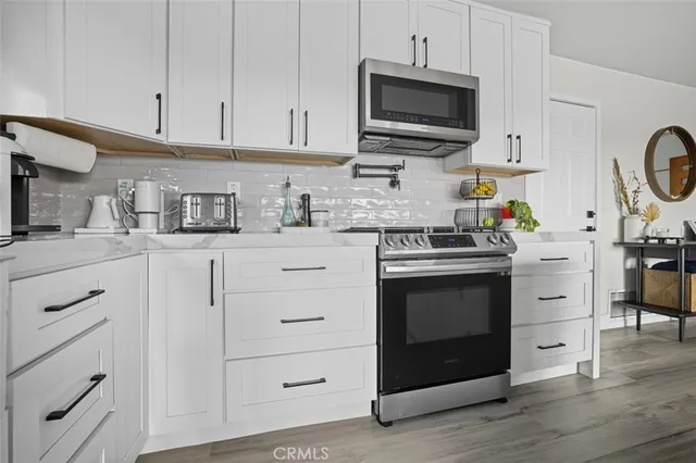 a kitchen with stainless steel appliances granite countertop a stove a sink and a microwave