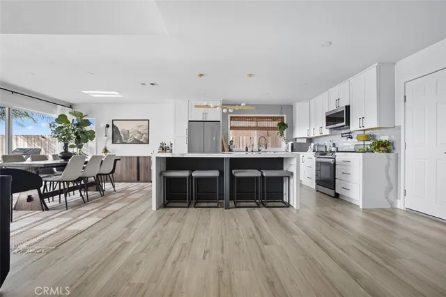 a kitchen with stainless steel appliances a kitchen island hardwood floor sink stove dining table and chairs