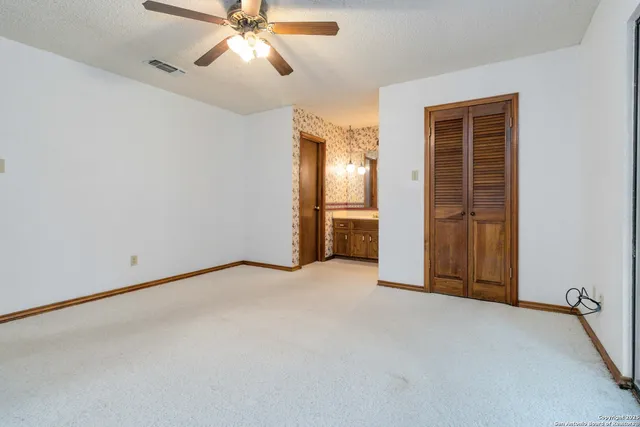 a view of an empty room and chandelier fan
