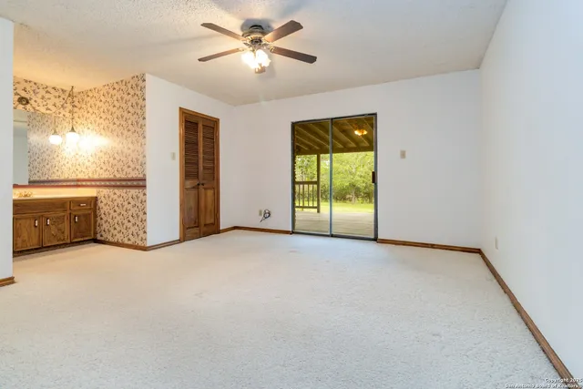 an empty room with chandelier fan and windows