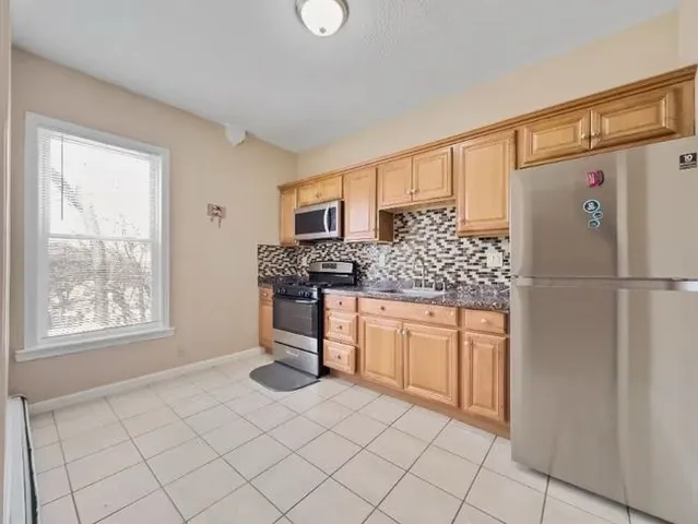 a kitchen with granite countertop white cabinets and refrigerator