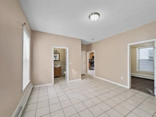 a view of an empty room with window and chandelier