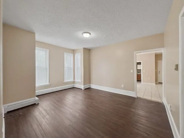 a view of an empty room with wooden floor and closet
