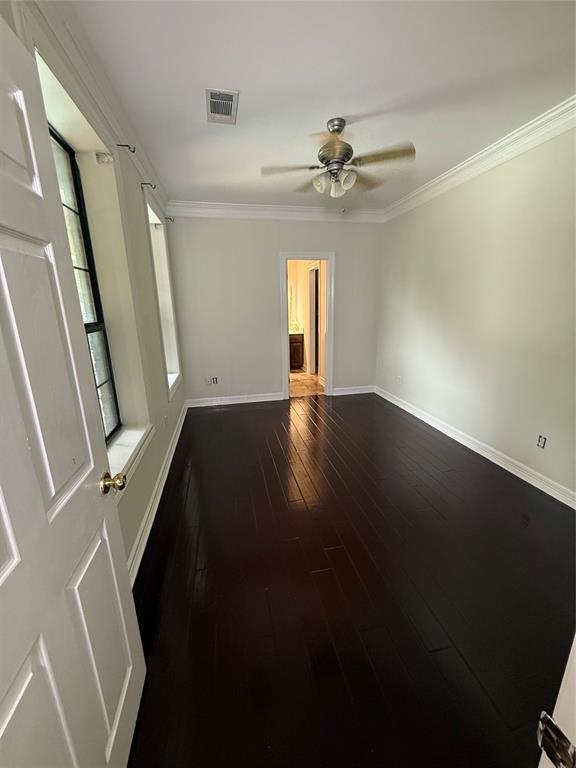 201 Woodhaven Drive Minden, LA 71055 - Photo 25 of 31 Room featuring dark wood-finish flooring, white crown molding, light-colored walls, and a ceiling fan with integrated lighting