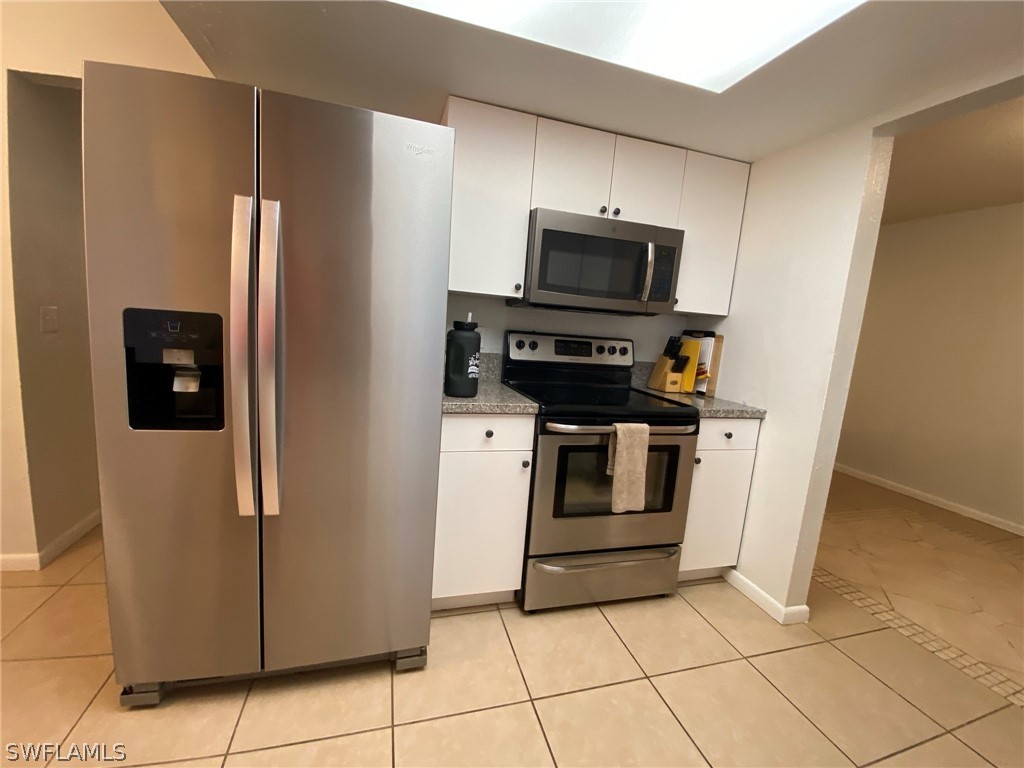 19157 Coconut Road Fort Myers, FL 33967 - Photo 9 of 26 a kitchen with white cabinets and stainless steel appliances