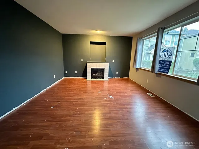 a view of an empty room with window and wooden floor