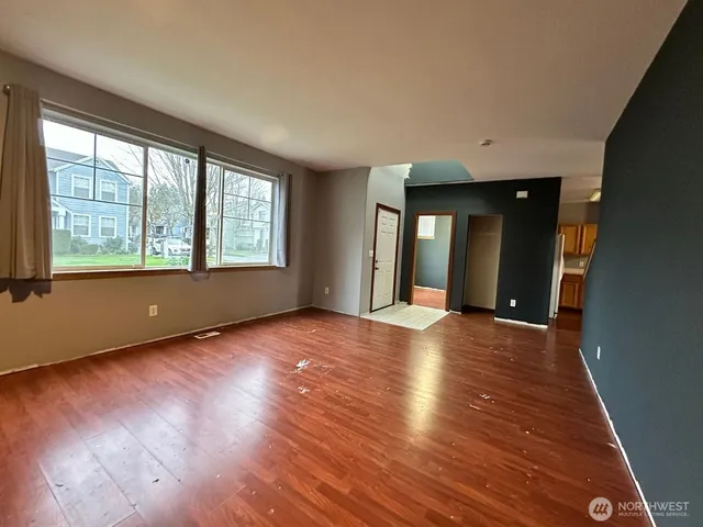 a view of an empty room with wooden floor and a window