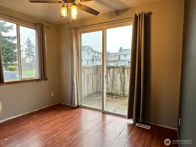 a view of an empty room with wooden floor and a window