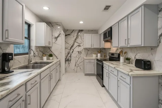 a kitchen with white cabinets and sink
