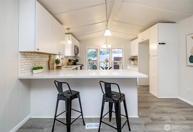 a kitchen with stainless steel appliances granite countertop a stove top oven a sink dishwasher a dining table and chairs with wooden floor