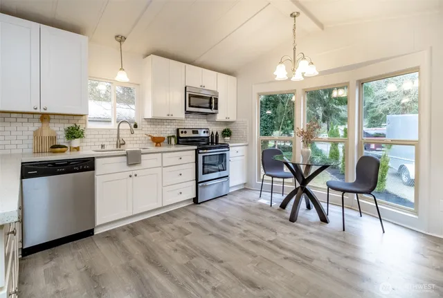 a kitchen with cabinets stainless steel appliances and wooden floor
