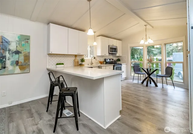 a kitchen with stainless steel appliances kitchen island granite countertop a table chairs sink and cabinets