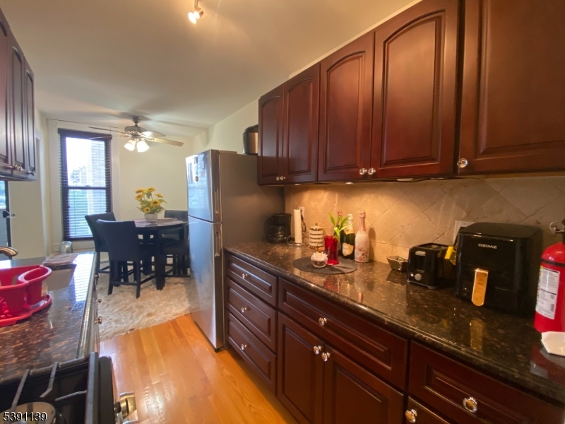824 Main Street, Unit J Belleville, NJ 07109 - Photo 12 of 24 a kitchen with granite countertop wooden cabinets a table and chairs
