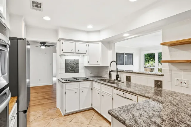 a large white kitchen with stainless steel appliances a refrigerator and a stove top oven