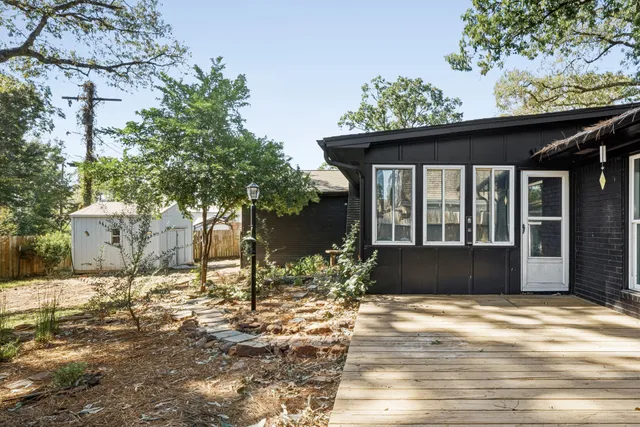 a backyard of a house with table and chairs under an umbrella
