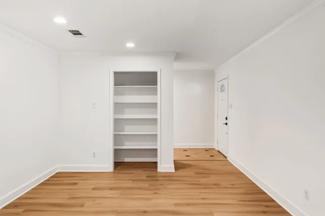 a view of an empty room with a window and a kitchen