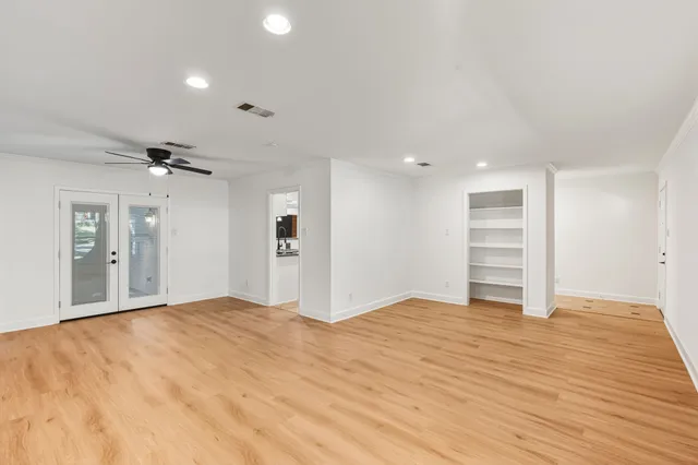 a view of empty room with wooden floor and ceiling fan