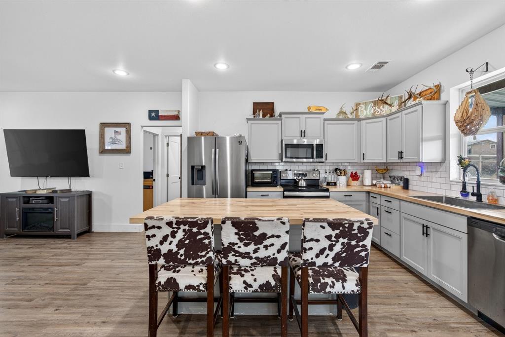 2225 West J E Woody Road Springtown, TX 76082 - Photo 5 of 29 Open-concept kitchen featuring light gray cabinetry, wood-finish countertops, stainless steel appliances, and a subway tile backsplash