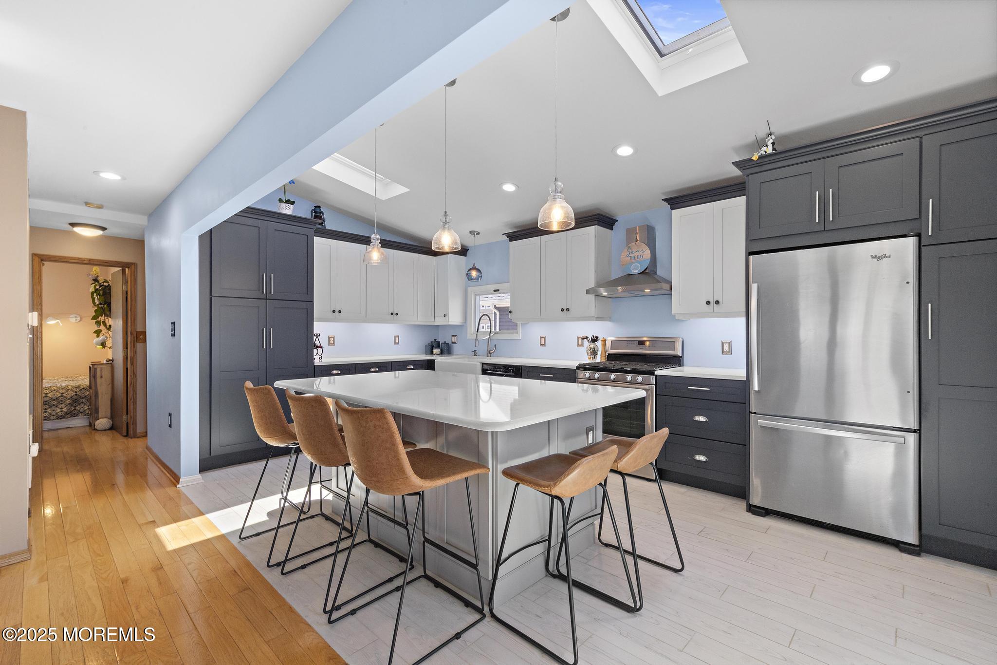 68 Patrick Drive Beach Haven West, NJ 08050 - Photo 5 of 16 a kitchen with stainless steel appliances a refrigerator a stove a sink and a dining table with wooden floor