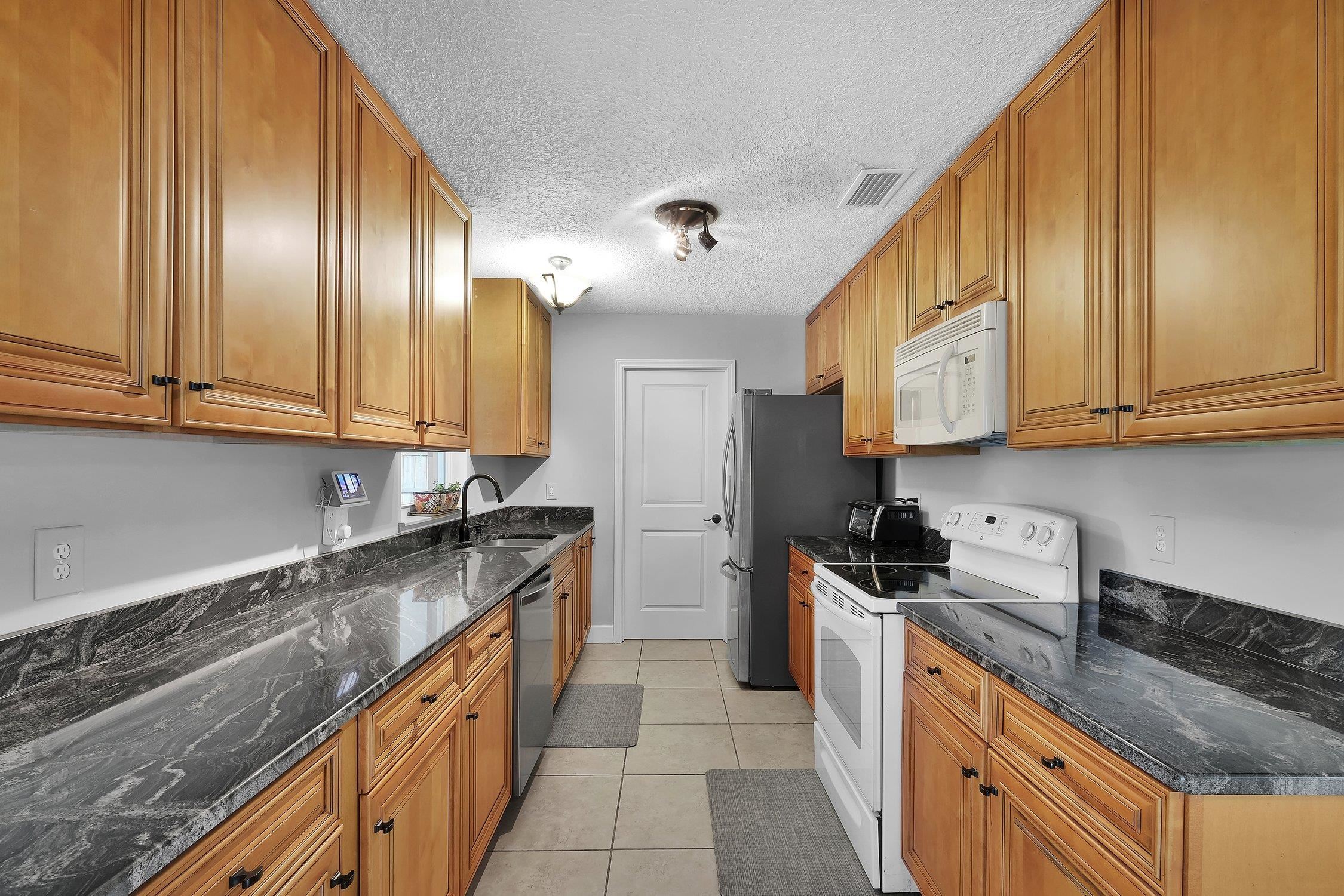 141 Argonaut Road St. Augustine, FL 32086 - Photo 11 of 27 a kitchen with granite countertop cabinets stainless steel appliances a sink and wooden floor