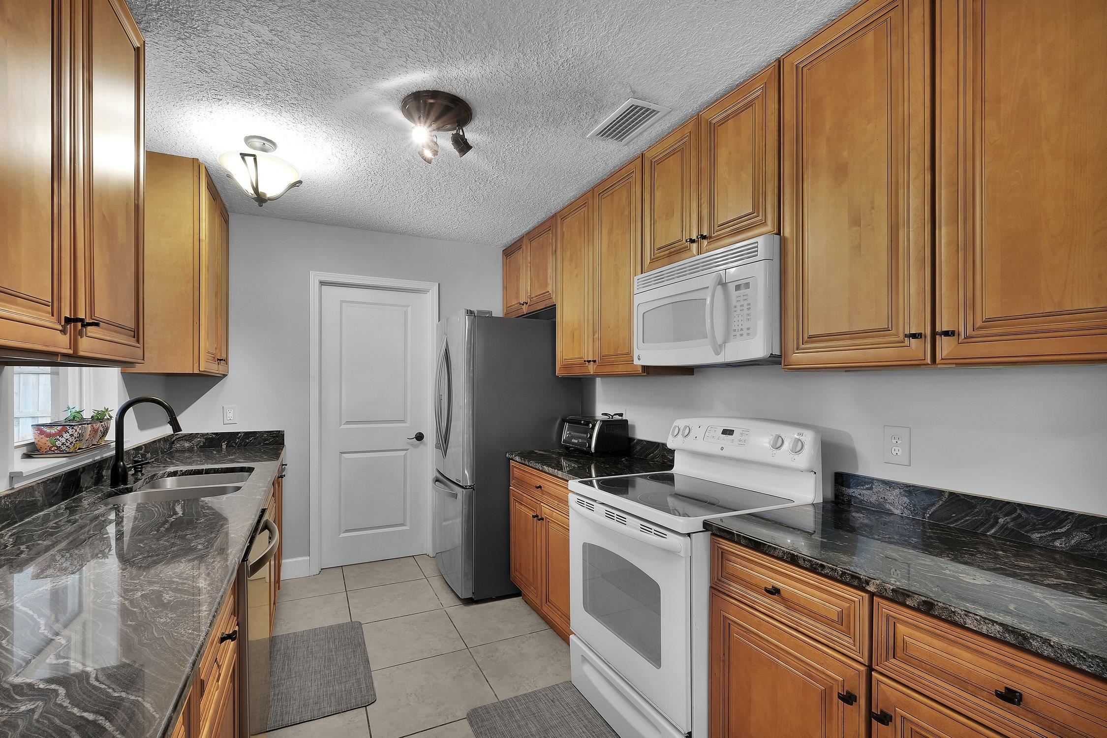 141 Argonaut Road St. Augustine, FL 32086 - Photo 12 of 27 a kitchen with stainless steel appliances granite countertop a sink stove and cabinets