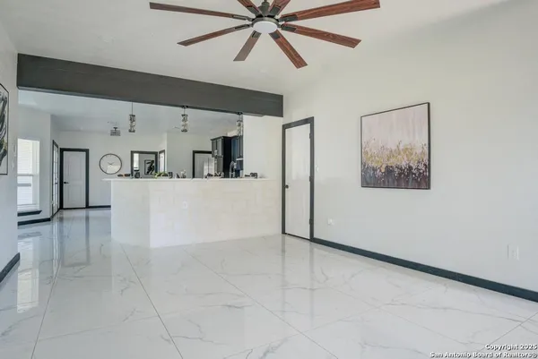 a view of a livingroom with a ceiling fan & cabinets