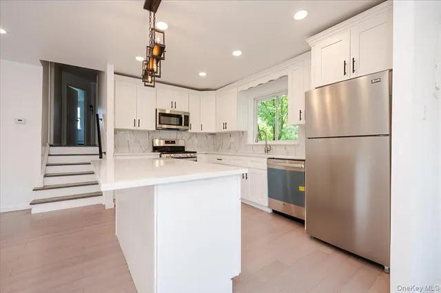 a kitchen with a refrigerator a stove top oven a sink and cabinets