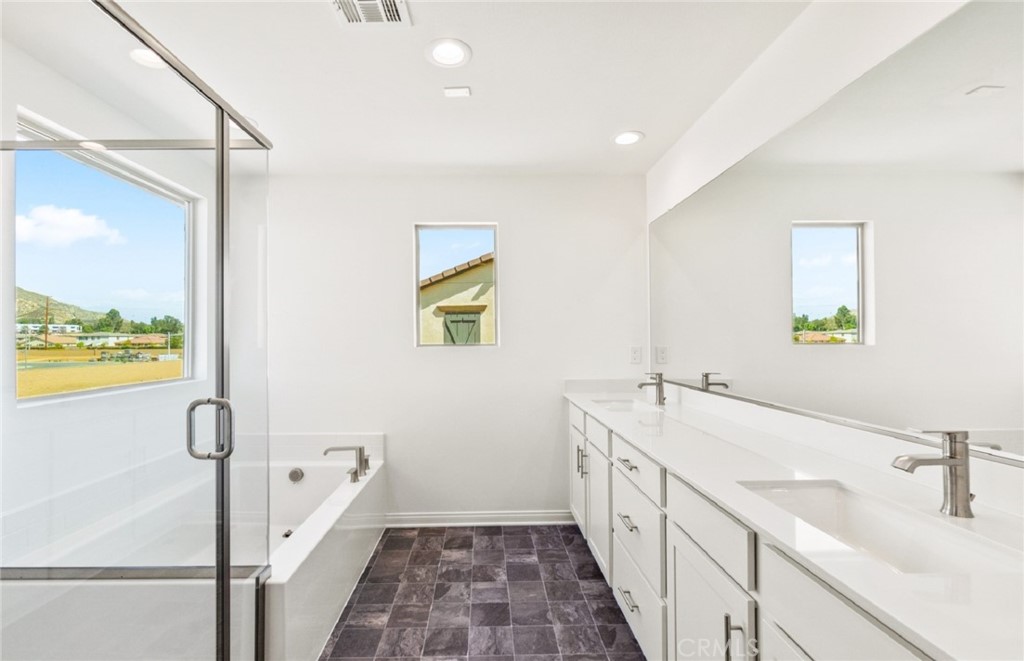 784 Sawgrass Street Perris, CA 92571 - Photo 31 of 46 a bathroom with a double vanity sink a mirror and a bathtub