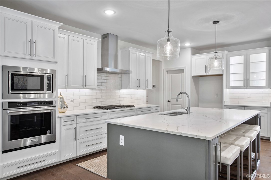 a kitchen with stainless steel appliances granite countertop a sink a stove a refrigerator and white cabinets