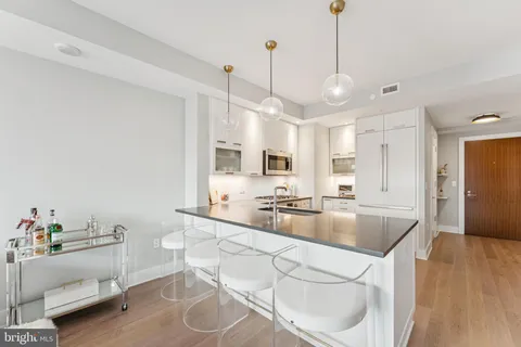 a large kitchen with kitchen island a stove a sink a center island and wooden floor