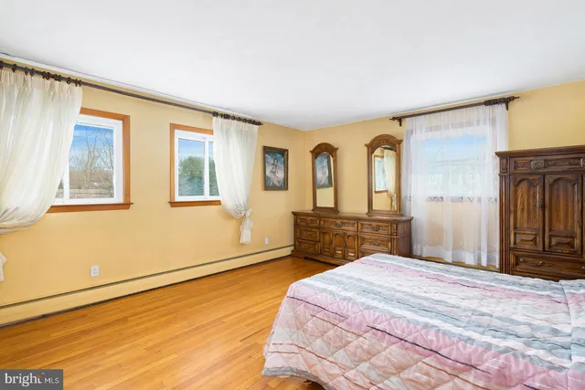 a bedroom with a bed dresser and a large window