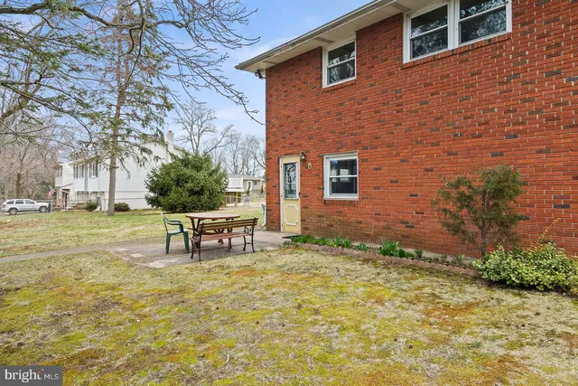 a view of a brick wall with a bench in the backyard