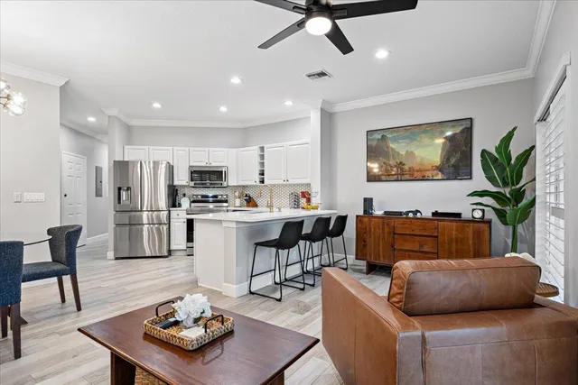 a living room with furniture kitchen view and a potted plant