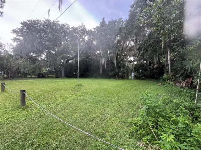a view of a field with a big yard and large trees