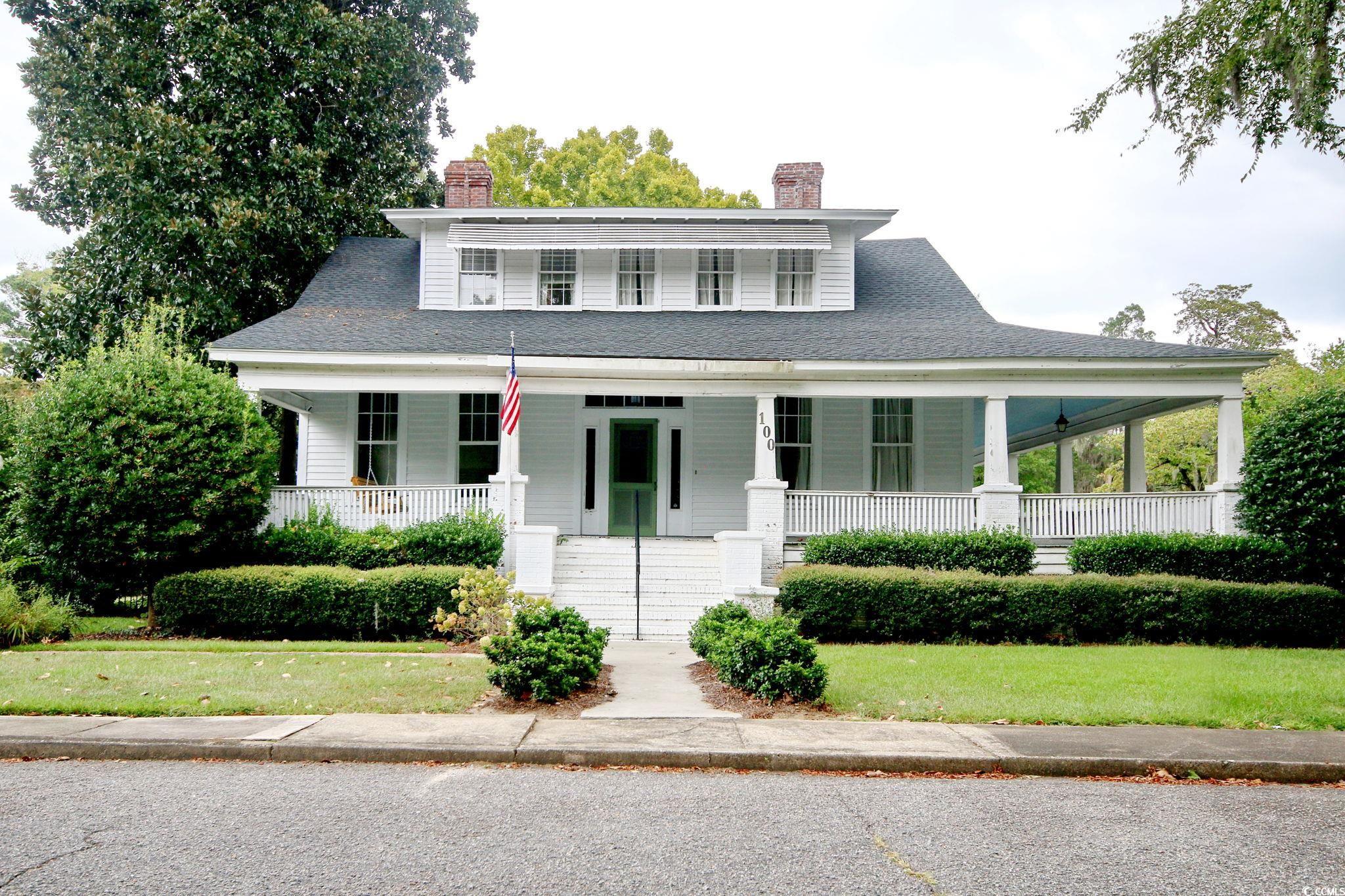 Farmhouse-style home featuring a porch, a shingled roof, and a front lawn
