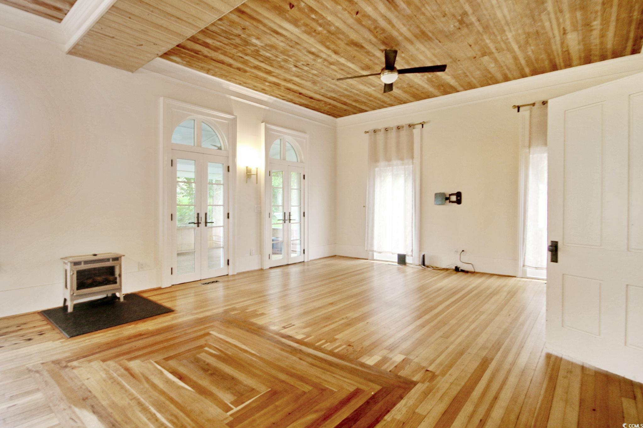 100 Northeast Ct Street Marion, SC 29571 - Photo 23 of 40 Unfurnished living room featuring a wood stove, french doors, wooden ceiling, a ceiling fan, and hardwood / wood-style floors