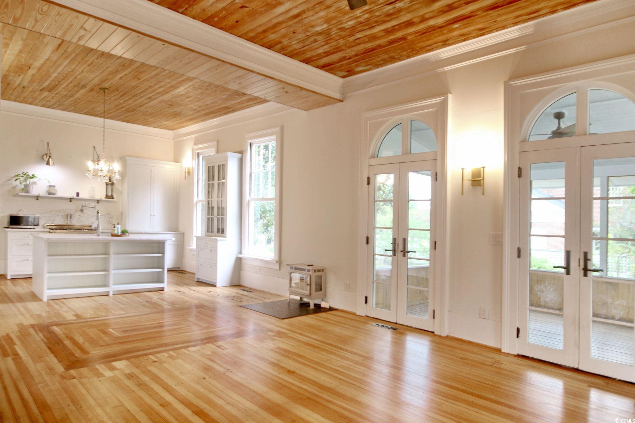 100 Northeast Ct Street Marion, SC 29571 - Photo 25 of 40 Unfurnished living room with wood ceiling, crown molding, light wood-style floors, french doors, and a chandelier