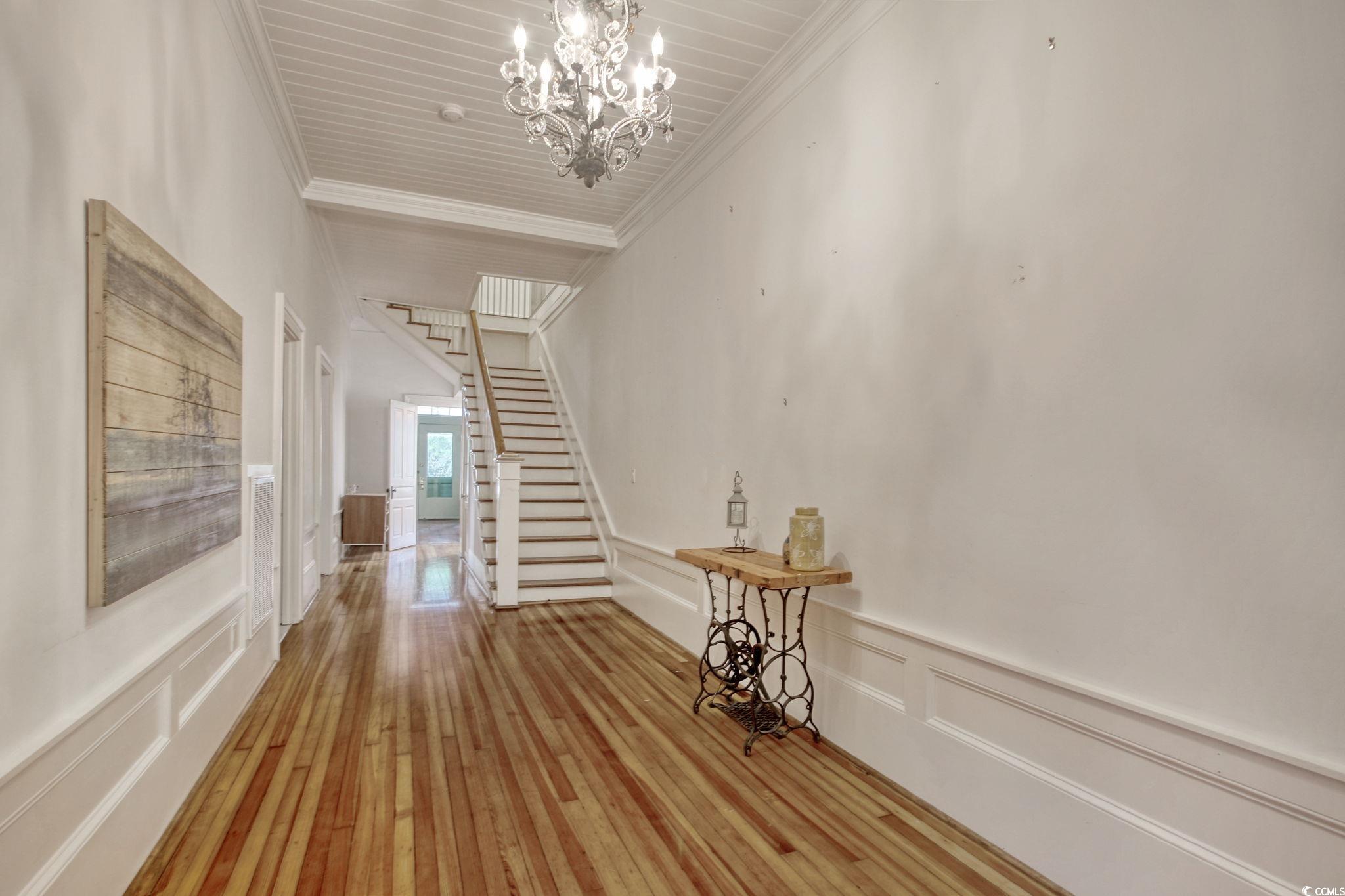 100 Northeast Ct Street Marion, SC 29571 - Photo 26 of 40 Corridor with a decorative wall, crown molding, wainscoting, stairs, and a chandelier