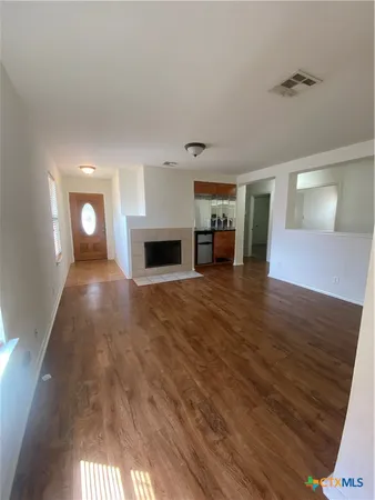 a view of empty room with wooden floor and fireplace