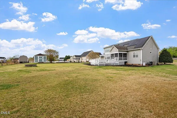 a white house that has a large pool with a yard and plants