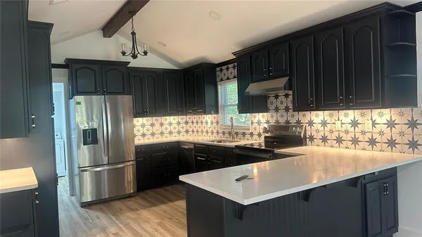 a kitchen with stainless steel appliances wooden cabinets a sink and a refrigerator