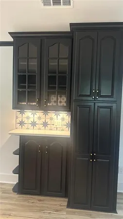 an empty room with wooden floor cabinet and windows