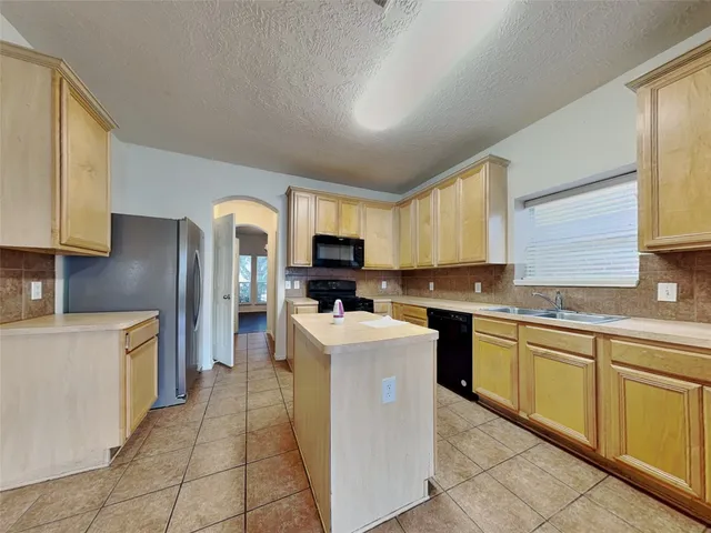 a kitchen with stainless steel appliances granite countertop a stove top oven a sink a refrigerator and white cabinets