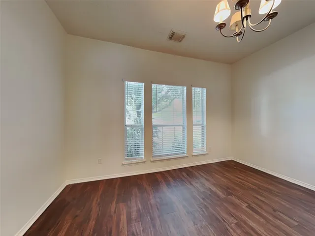 a view of an empty room with wooden floor and fan
