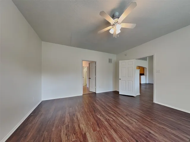 an empty room with wooden floor and ceiling fan