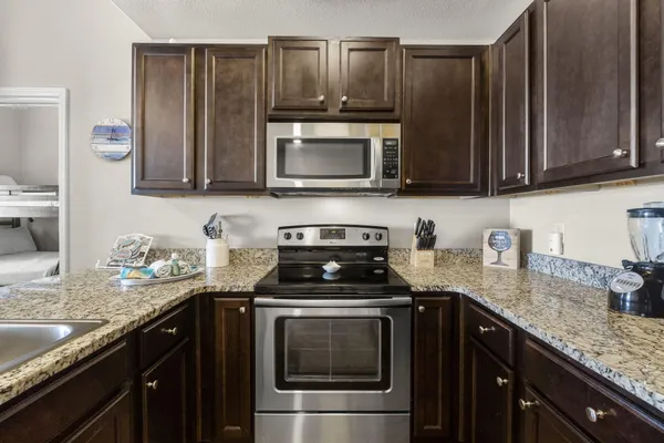 a kitchen with stainless steel appliances granite countertop a refrigerator a stove a sink a dining table and chairs