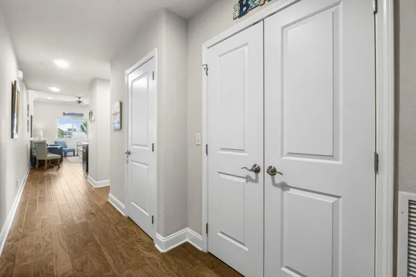 a view of a hallway with wooden floor closet and a bathroom