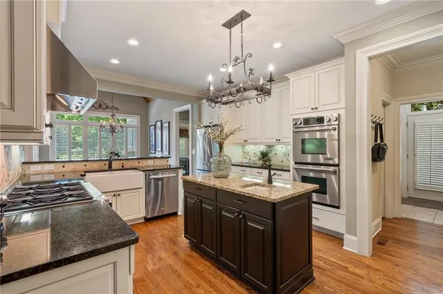 a kitchen with stainless steel appliances kitchen island granite countertop a refrigerator and wooden floor