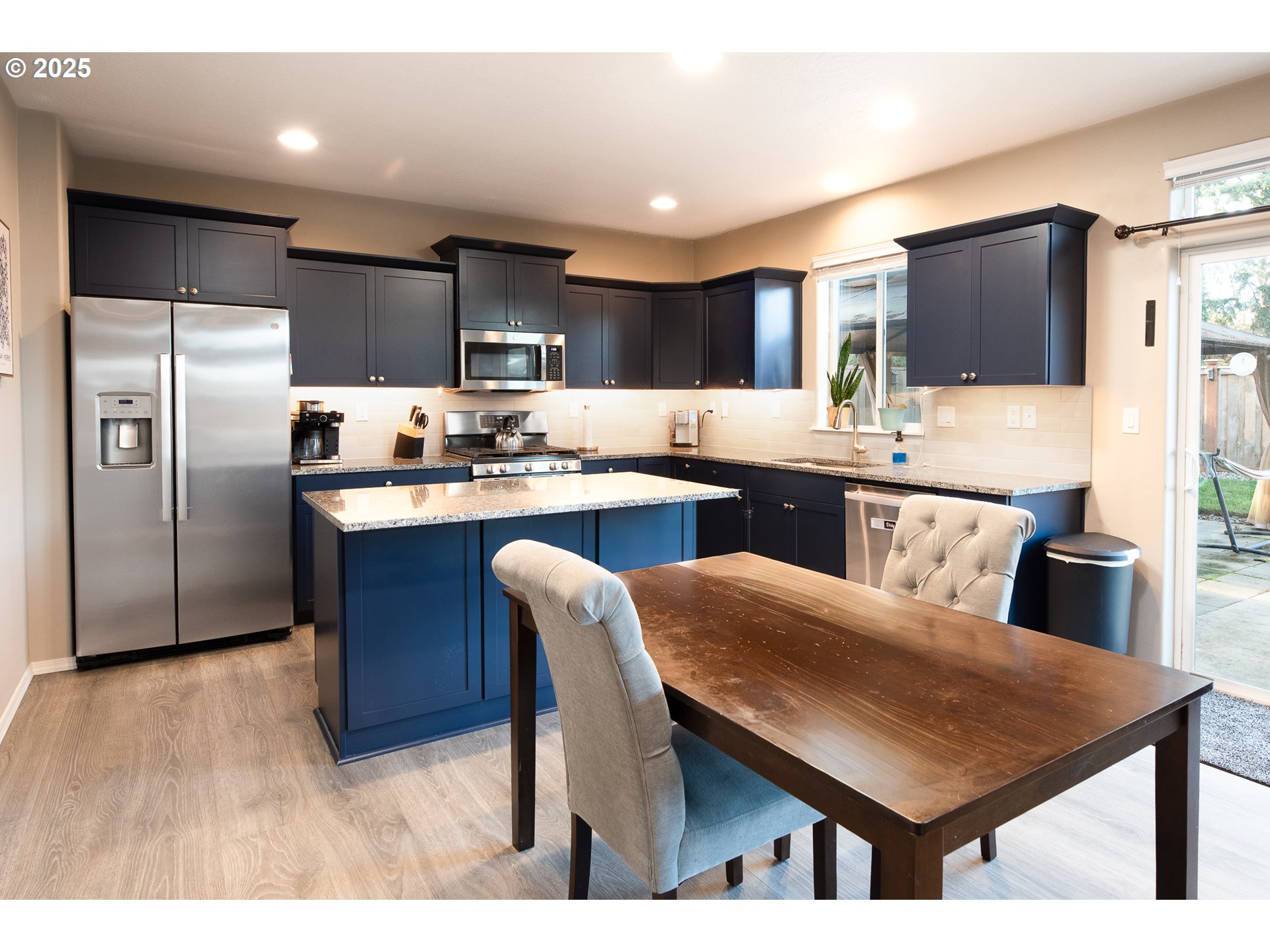 792 South 52nd Place Springfield, OR 97478 - Photo 8 of 45 a kitchen with stainless steel appliances kitchen island granite countertop a table chairs microwave and refrigerator
