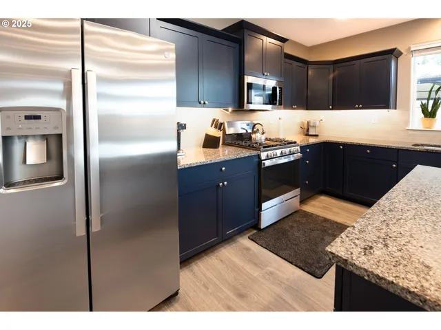 a kitchen with stainless steel appliances kitchen island granite countertop a refrigerator and a sink